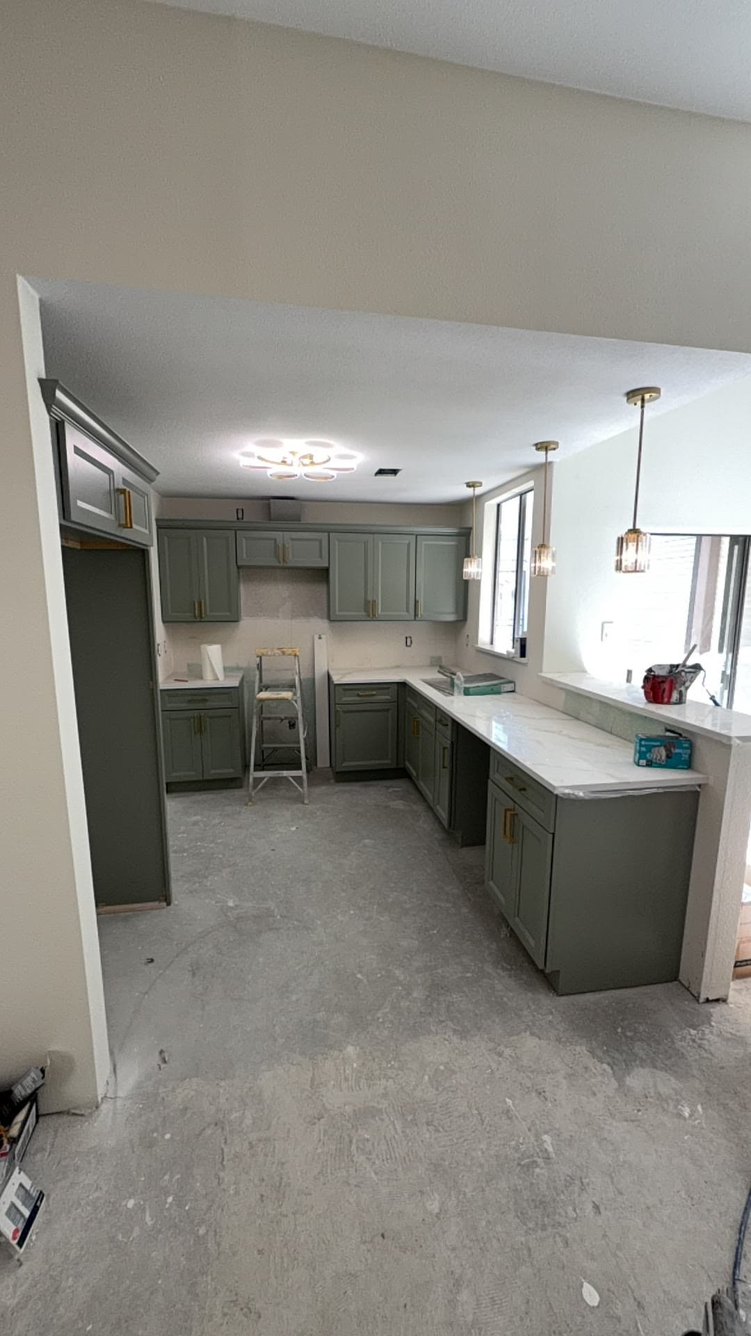 The same kitchen with sage shaker cabinets, quartz counters, a new island and pendant lighting