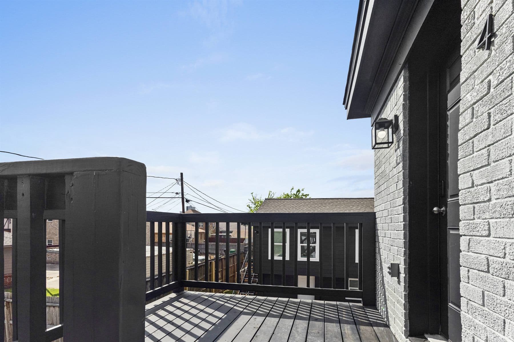 Black wood rooftop deck with railing under open sky, finished by the Reborn group