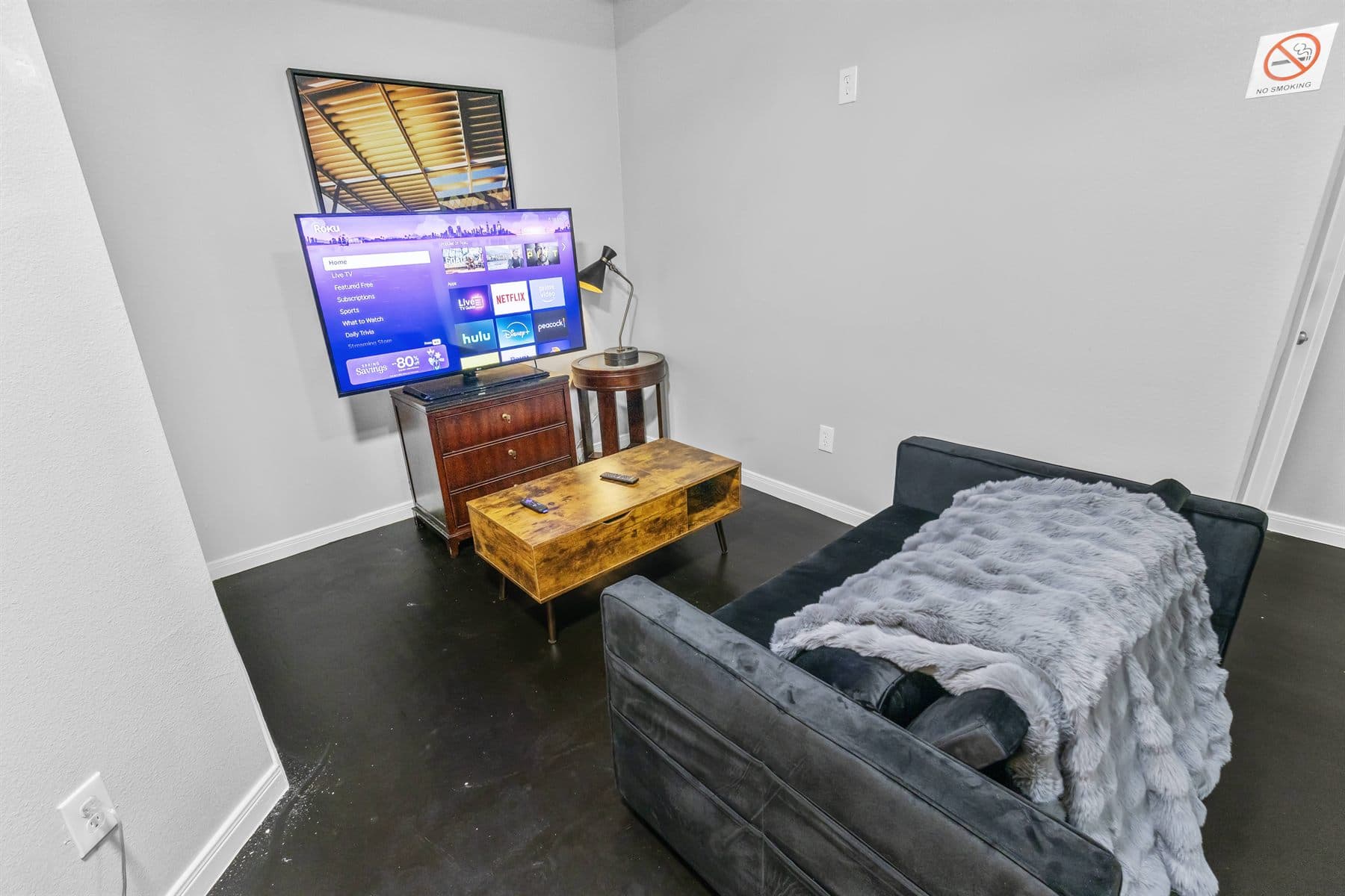 Living room with charcoal sectional and wall-mounted TV, finished by the Reborn group
