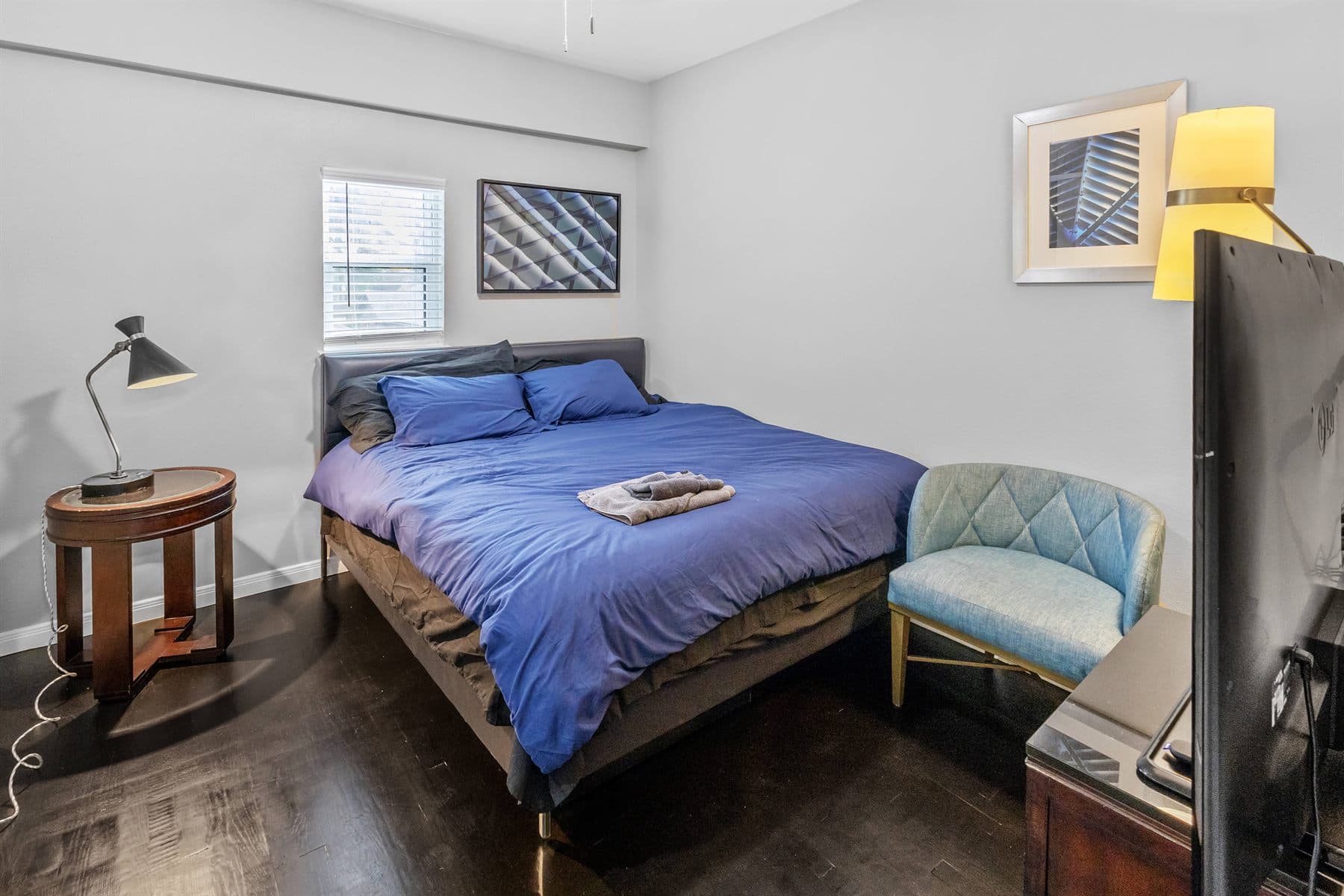 Bedroom with navy bedspread and blue accent chair, finished by the Reborn group