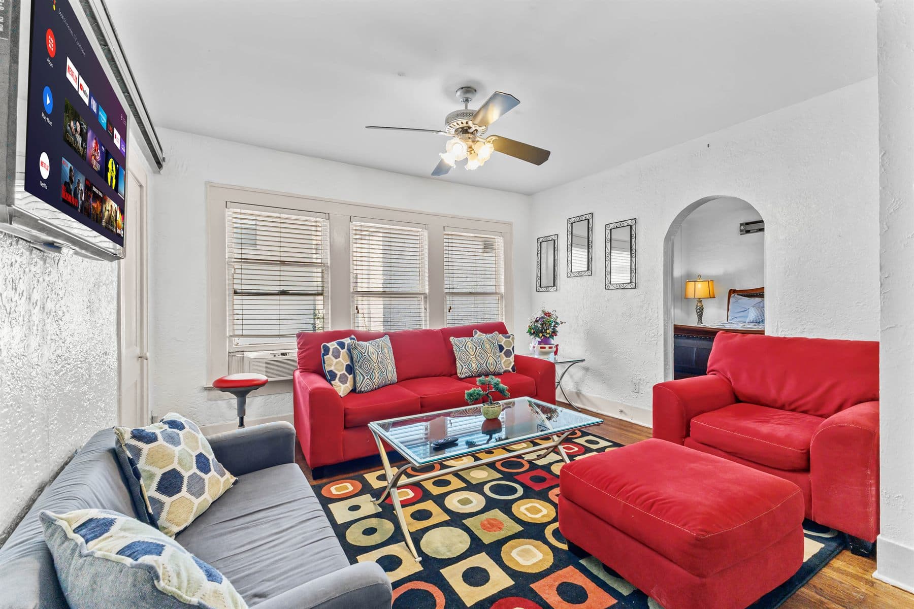 Living room with red sofa, patterned rug and arched doorway, finished by the Reborn group