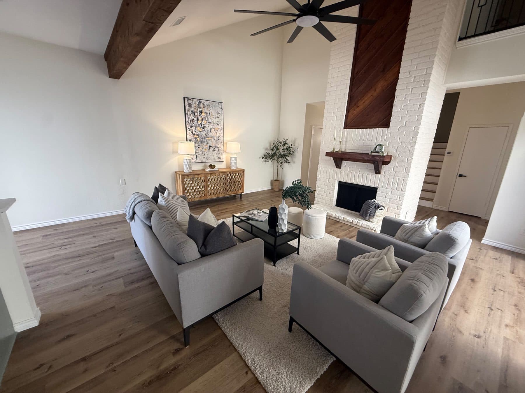 Living room seen from the upstairs landing, with the vaulted ceiling, exposed beam and painted fireplace, staged for listing and finished by the Reborn group