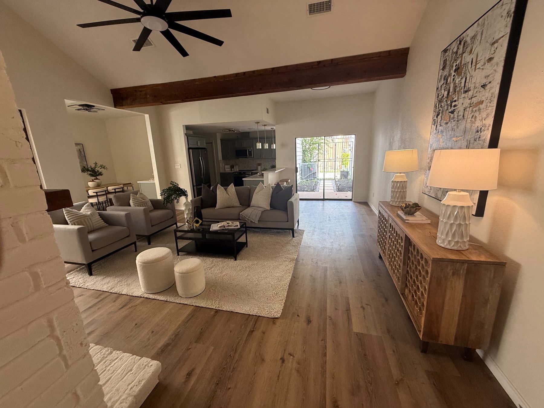 Living room console against the white-painted brick wall under the beam, staged for listing and finished by the Reborn group