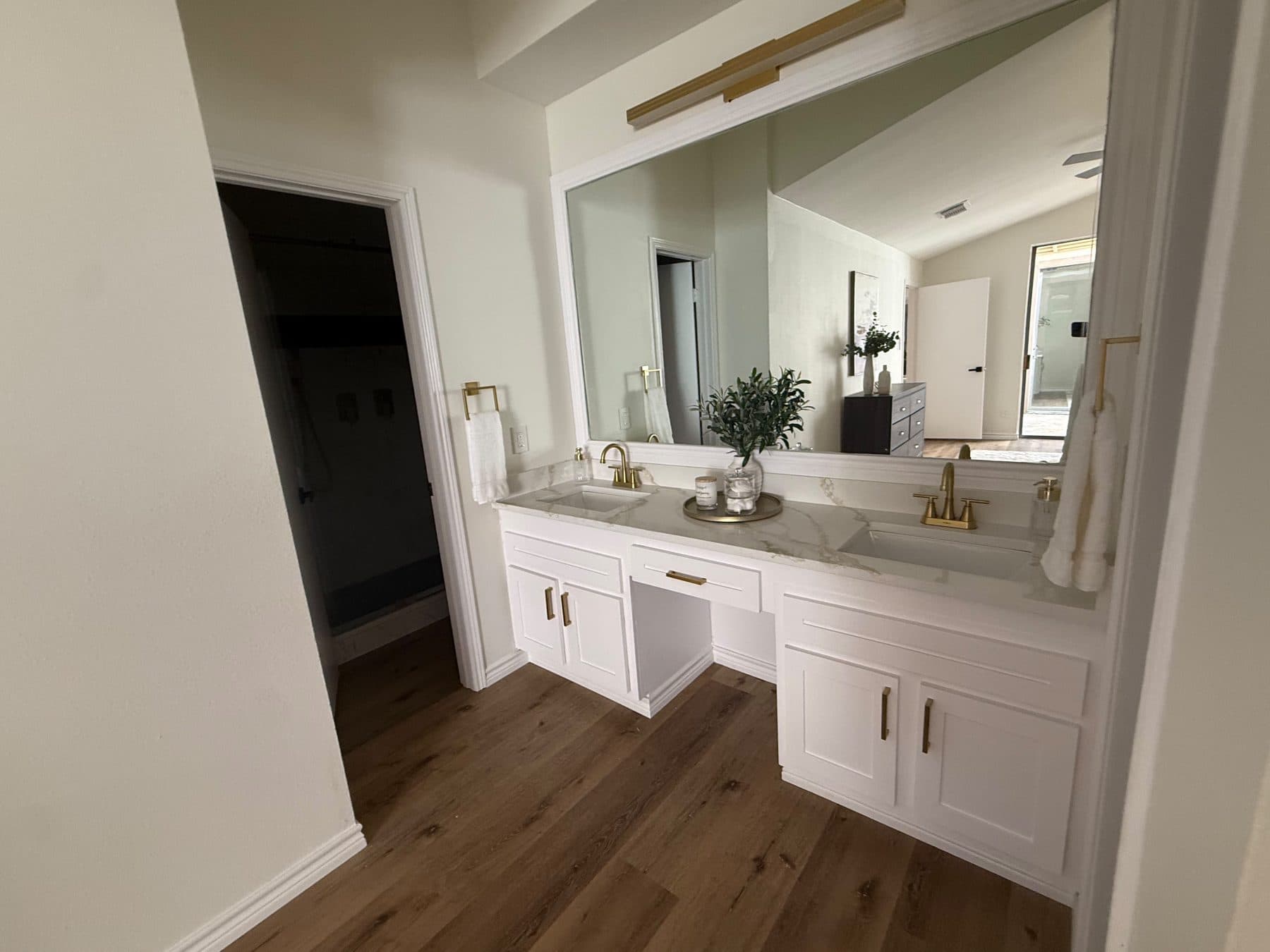 Primary bath with a white double vanity, quartz top and brushed-gold fixtures, finished by the Reborn group