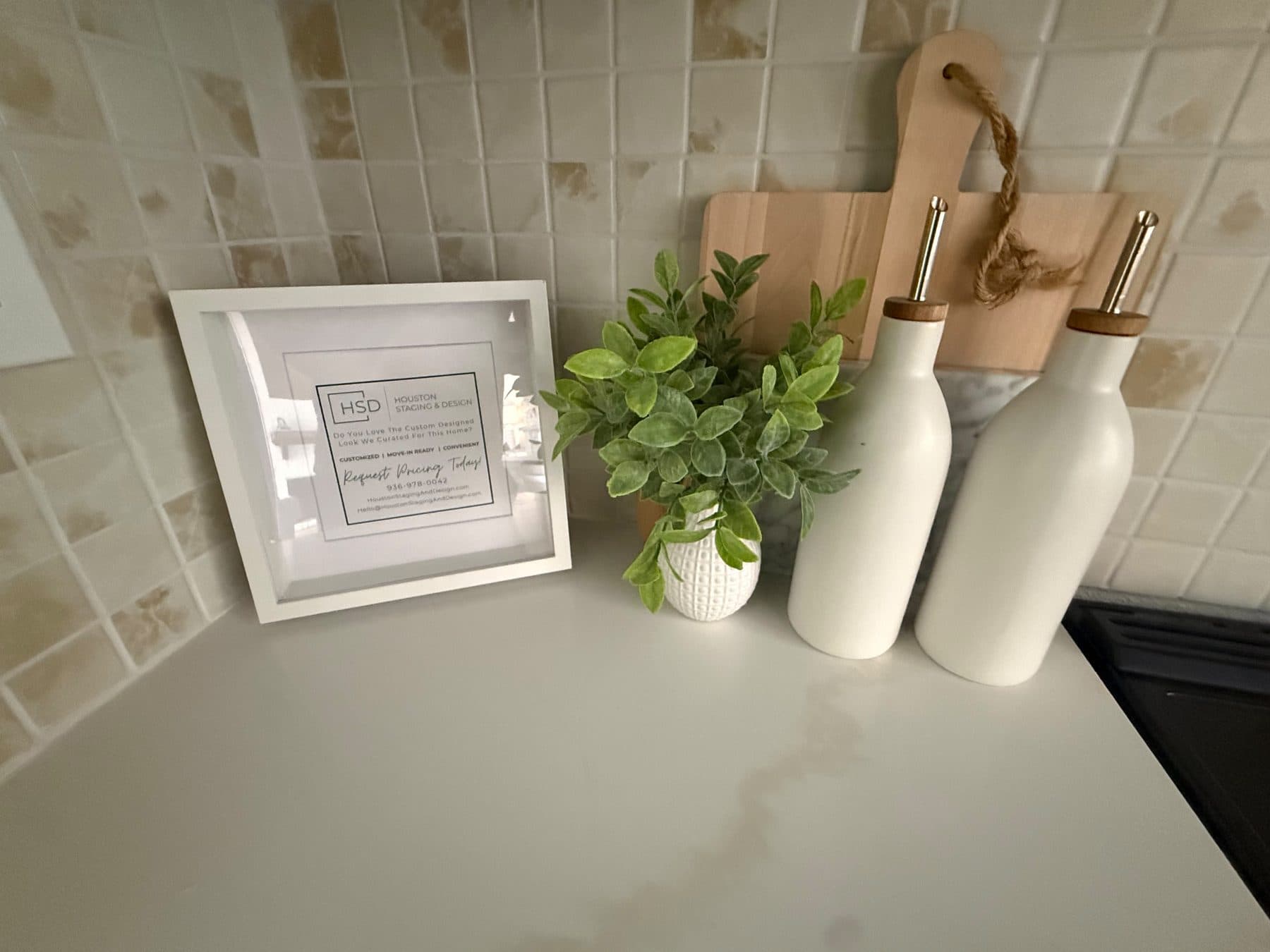 Kitchen backsplash tile and quartz counter styled with bottles and greenery, staged for listing and finished by the Reborn group