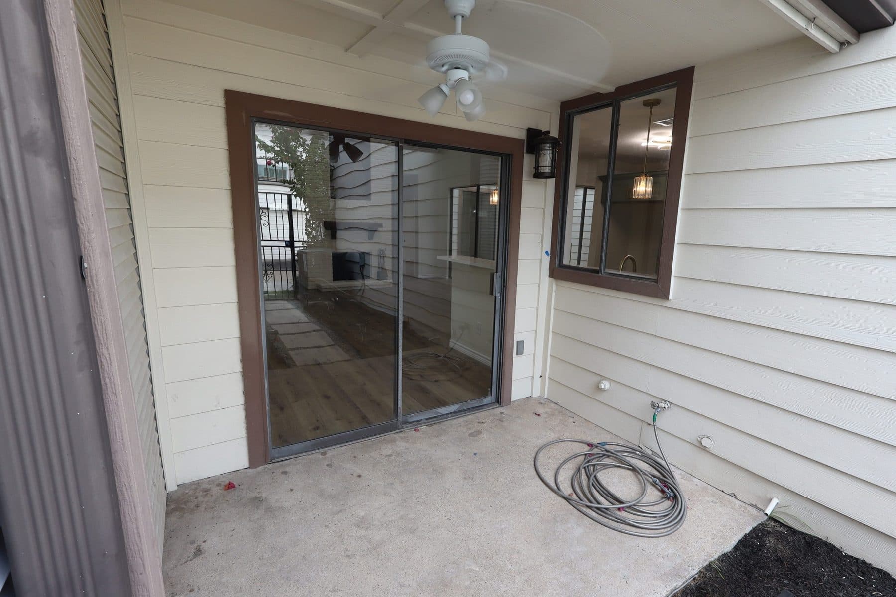 Covered back patio with a new ceiling fan and sliding door, finished by the Reborn group
