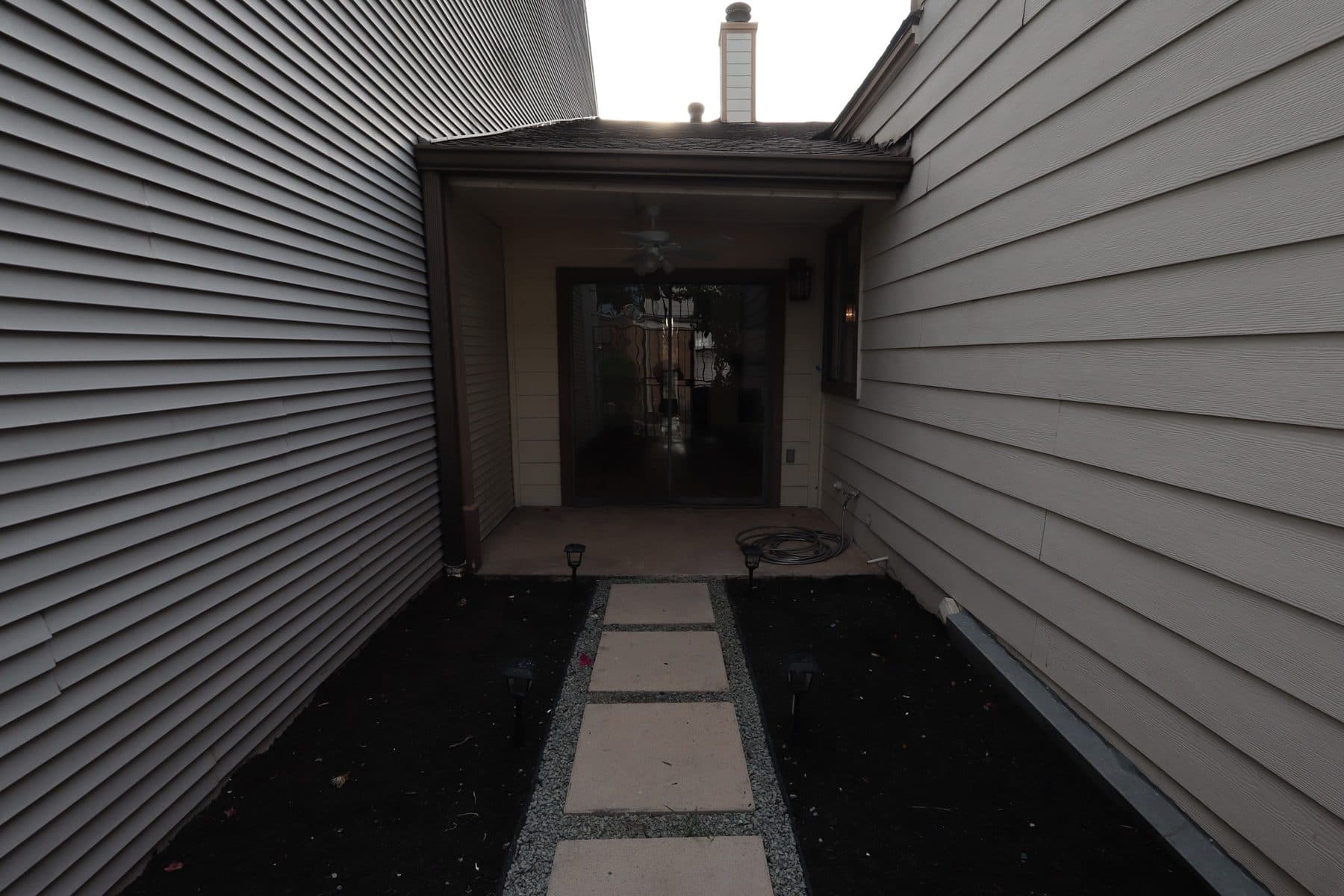 Covered side walkway re-laid with pavers set in gravel, finished by the Reborn group
