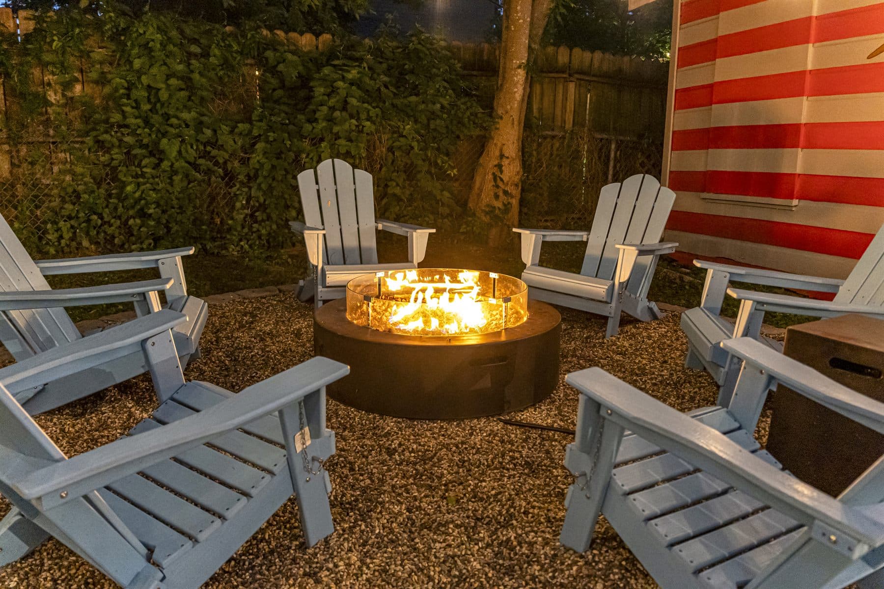 Backyard fire pit lounge at dusk with glowing string lights, finished by the Reborn group