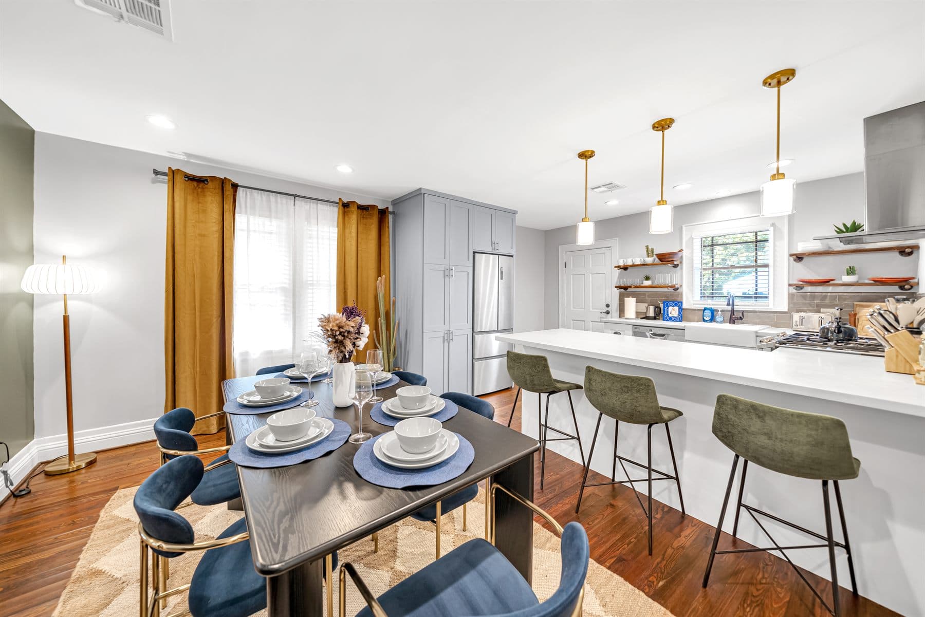 Open kitchen and dining with gold pendants and gallery wall, finished by the Reborn group