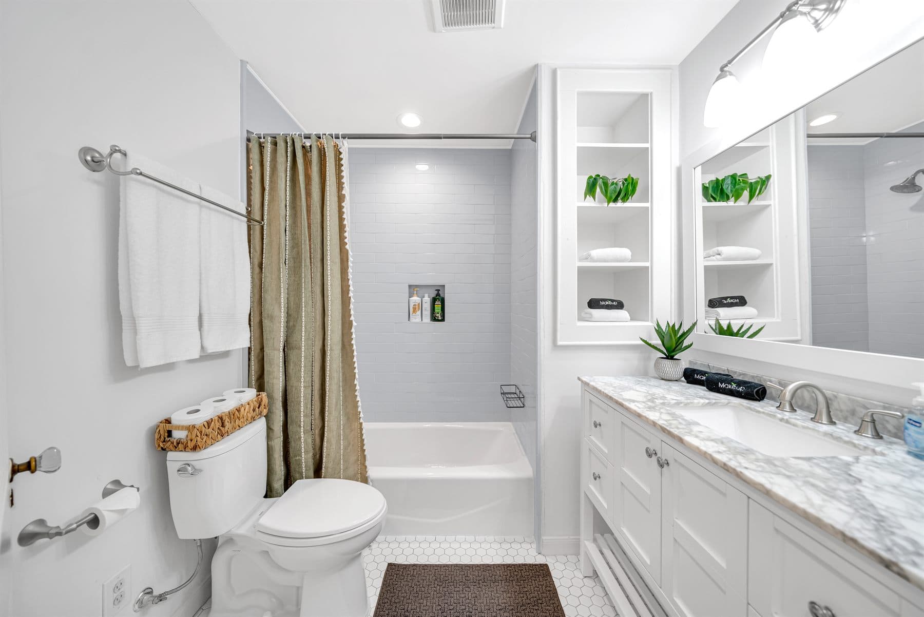 Marble-look vanity with glass walk-in shower and brass fixtures, finished by the Reborn group