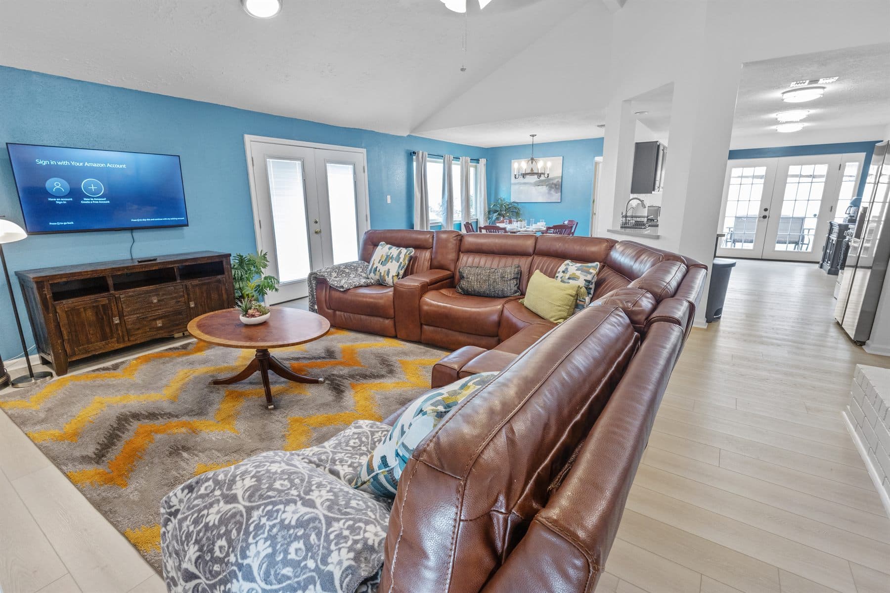 Living room with blue accent wall and brown leather sectional, finished by the Reborn group