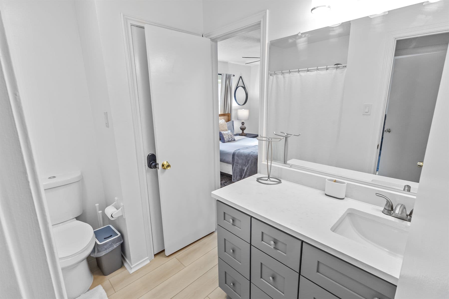 Bath with gray vanity and wall sconces, finished by the Reborn group
