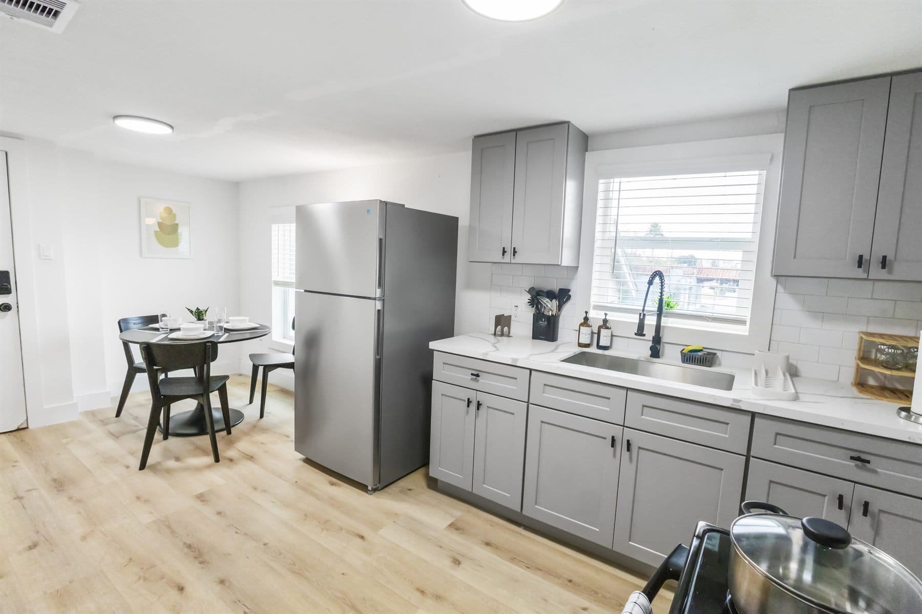 Wide kitchen with gray cabinets and small round table, finished by the Reborn group