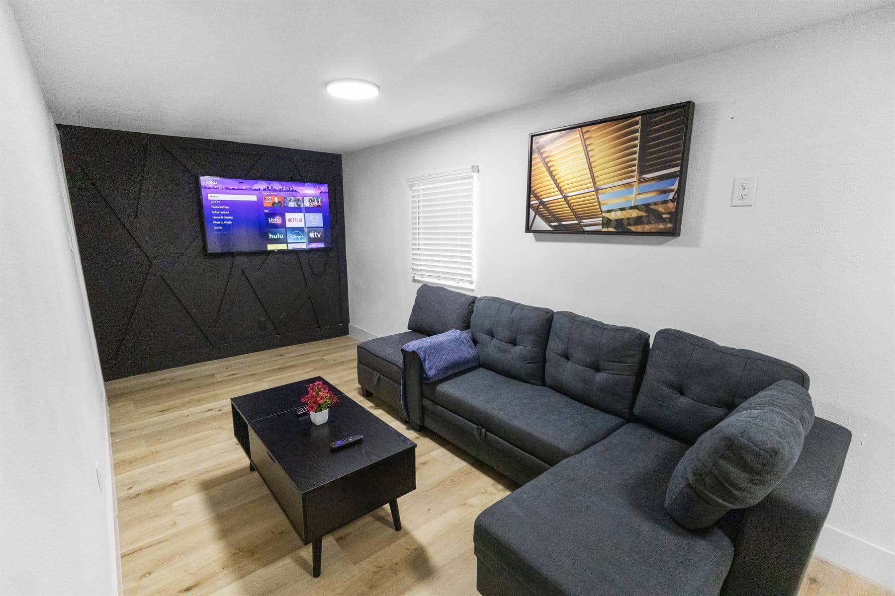 Living room with dark diagonal-slat accent wall and charcoal sectional, finished by the Reborn group