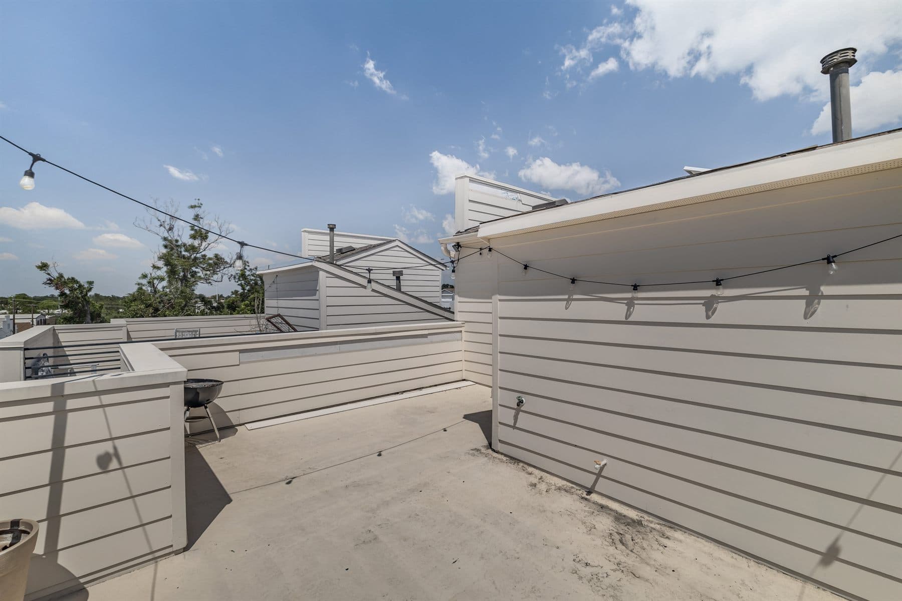 Rooftop patio with grill and string lights over neighboring rooftops, finished by the Reborn group