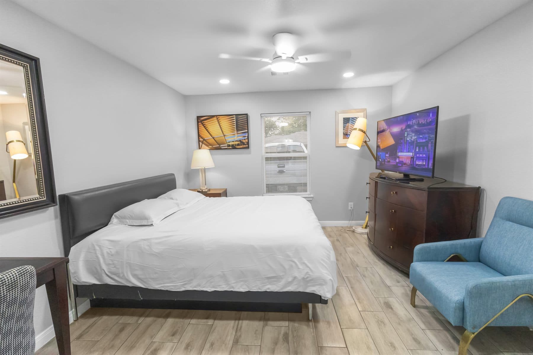 Staged bedroom with clean bedding and wood floor, finished by the Reborn group