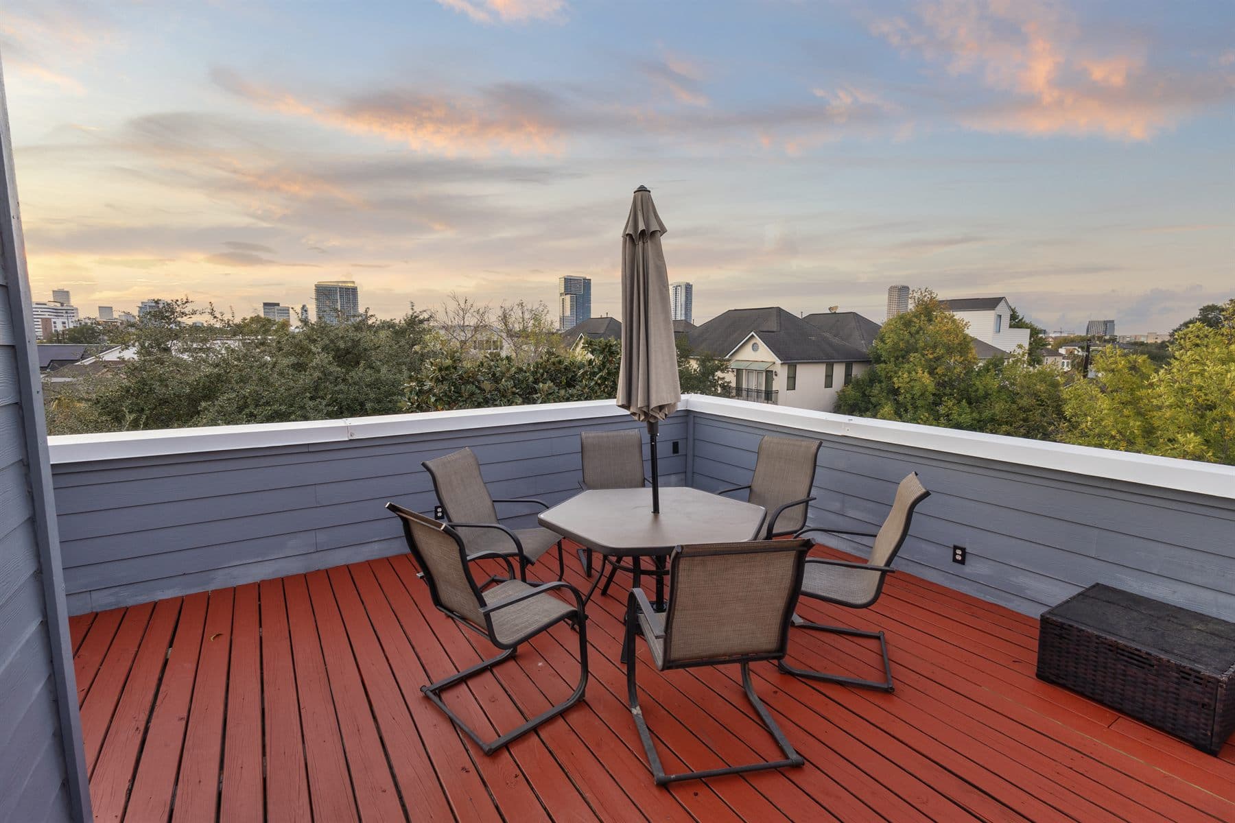 Rooftop deck with outdoor dining set at sunset over the city skyline, finished by the Reborn group