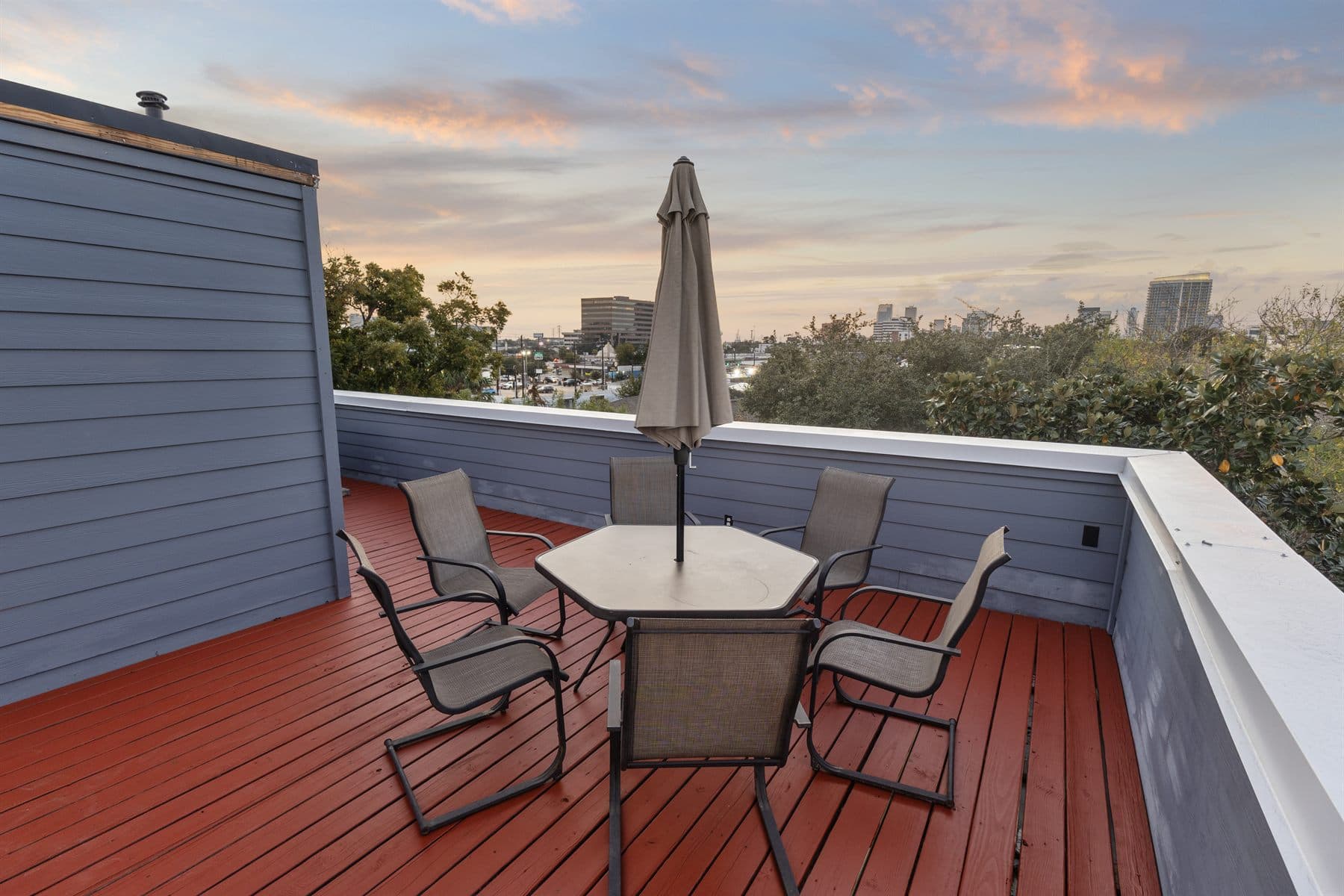 Rooftop terrace with umbrella table and lounge chairs above the treetops, finished by the Reborn group